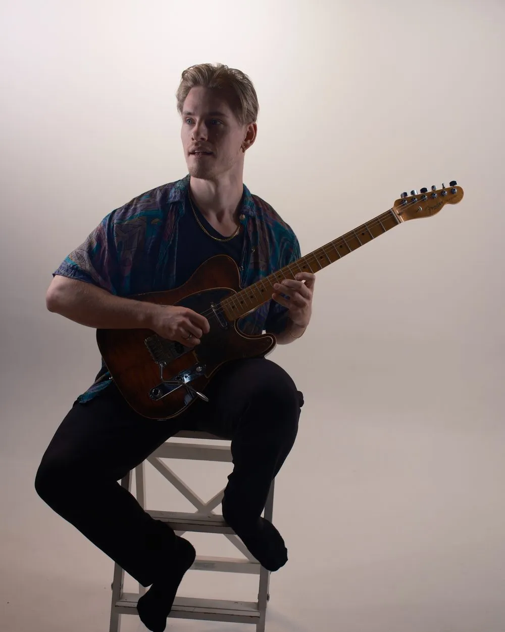 Eirik sitter med gitar, i silhuett
