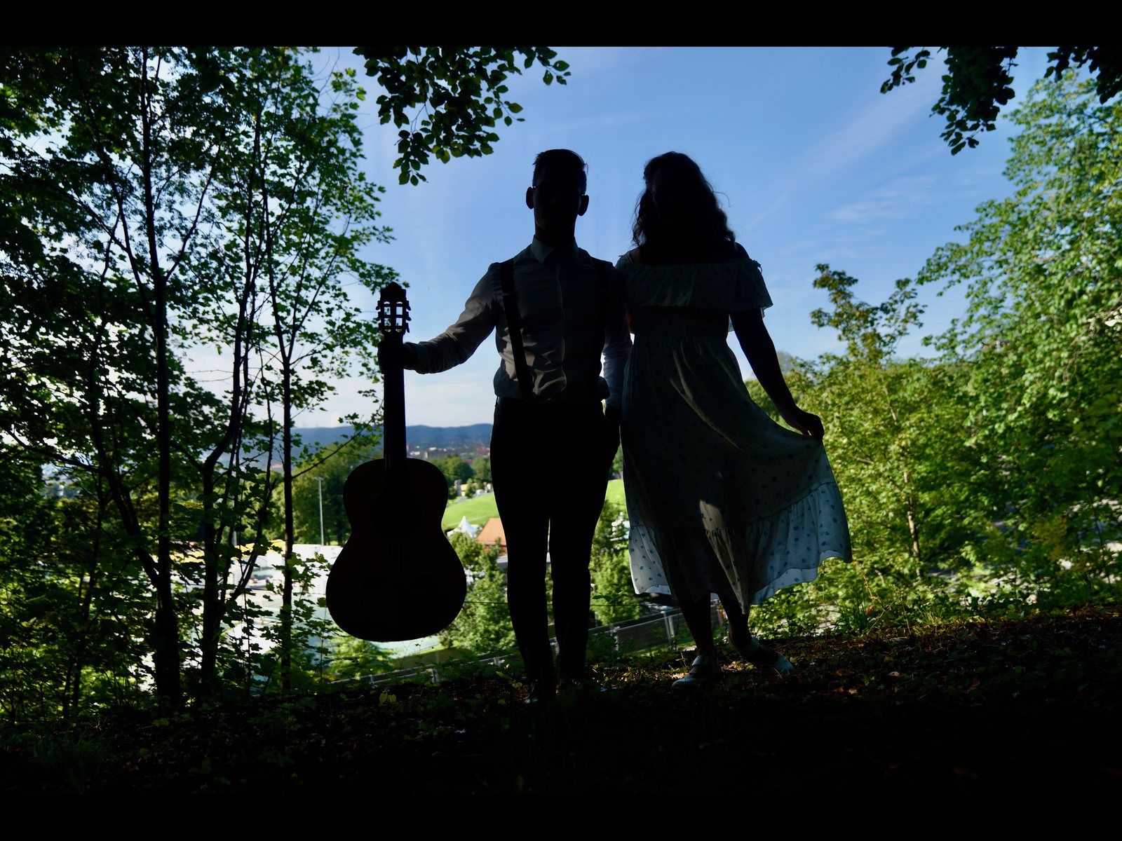Rebekka og Eirik i silhuett mot kveldshimmelen, Eirik med gitar